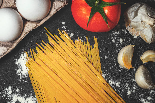 istock stack of raw pasta , eggs, tomatoes, garlic and flour on a black background 1292270987