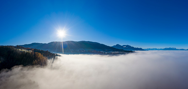 Aerial view of a sunrise at a foggy morning in autumn in the mountains. Photographed at the Linzenberg, Vorarlberg, Austria.