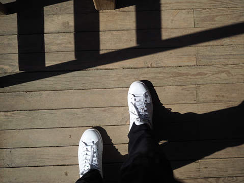 A White shoes wearing man standing with the shadows around