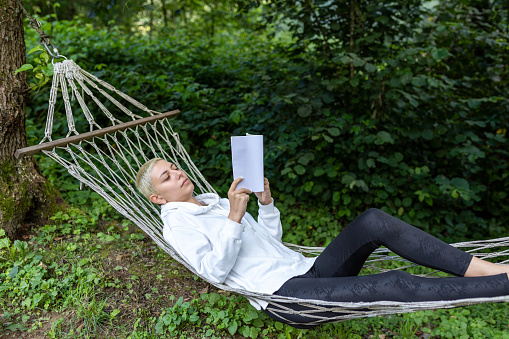 Woman reading a book while relaxing in hammock