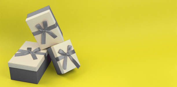 istock three closed gift box different sizes with gray ribbon bow on yellow paper background, present or surprise in trendy coolors for birthday or greeting holidays, banner with copy space 1292281269