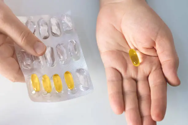 close-up view tablet of fish-oil supplement in man hand.