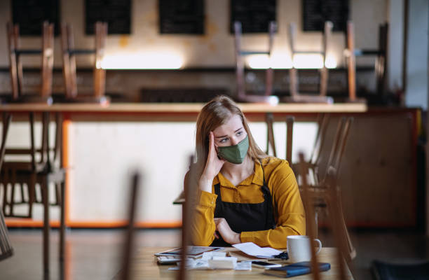 Frustrated owner sitting at table in closed cafe, small business lockdown due to coronavirus. Frustrated owner sitting at table in closed cafe or coffee shop, small business lockdown due to coronavirus. lockdown business stock pictures, royalty-free photos & images