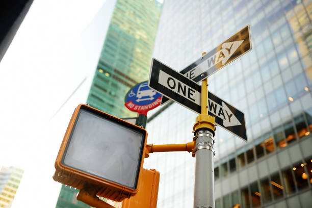 diferentes placas de trânsito com arranha-céus ao fundo em nova york, eua. sinalização de trânsito "ida" e semáforo para pedestres - one way stop stop sign street - fotografias e filmes do acervo