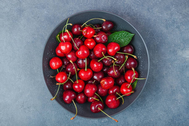 istock Cherry with leaf on plate and water dropsand on grey stone table 1292285853