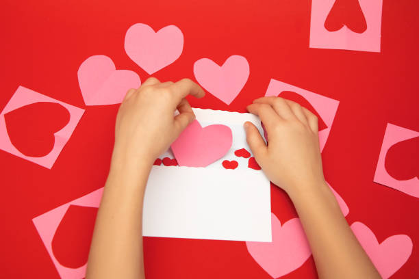 istock Valentine's day message in a white envelope on red background. Human hands fold hearts valentines 1292285867