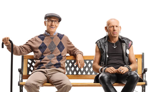 istock Elderly man with a cane and a punk man sitting on a bench 1292286920