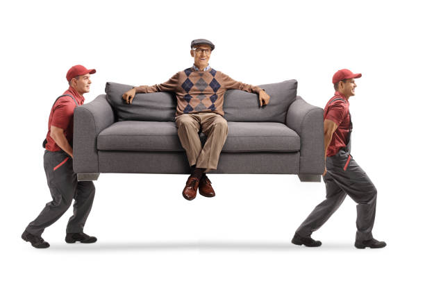 istock Movers carrying a sofa with an elderly man resting seated on the sofa 1292286937