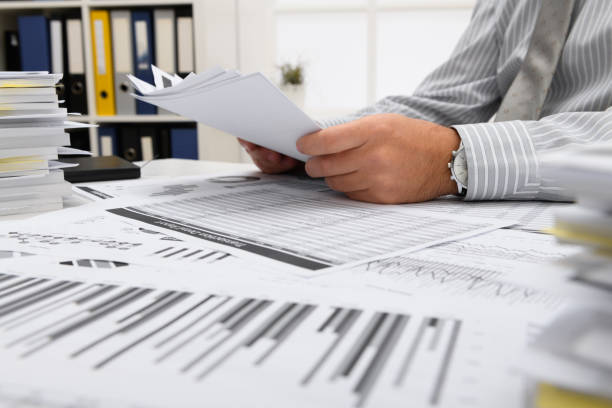 istock business concept - businessman working with reports in office, table and workspace close view, analyzing financial data, writes and counts 1292289442