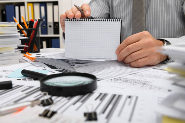 istock business concept - businessman working with reports in office, table and workspace close view, analyzing financial data, writes and counts 1292289513