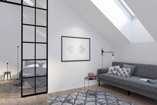 Modern attic with a horizontal poster on a white wall between a gray sofa with a coffee table and a glass partition. There are a roof window and a carpet on the wooden floor in the room. 3d render skylight stock pictures, royalty-free photos & images