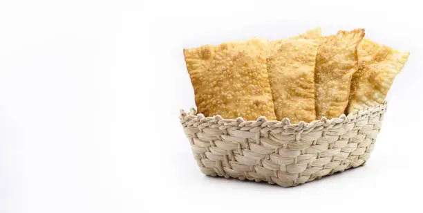 Photo of Brazilian pastry, traditional pastry called fried meat pastry, in straw basket, isolated on white background, copyspace