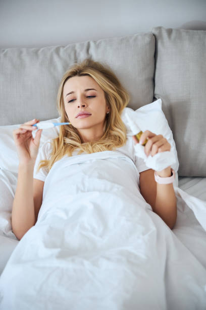 istock Young exhausted blonde woman checking her temperature 1292293885