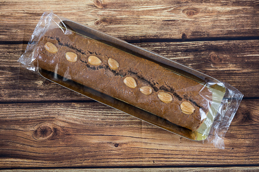 Top view of a dutch filled spiced bar for Sinterklaas on a wooden background.\nGevulde speculaas staaf, speculaaskoek.