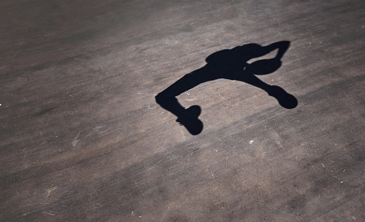 Shot of the shadow of a man throwing a basketball on a sports court