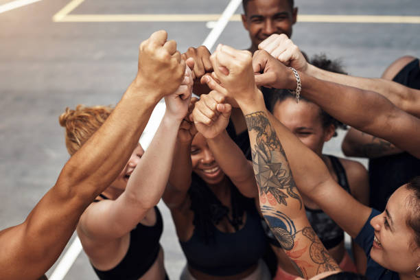 Teamwork means showing respect for each other Shot of a group of sporty young people standing together in a huddle on a basketball court team sport stock pictures, royalty-free photos & images