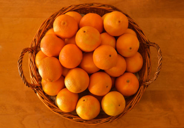 Clementines in a wicker basket on a wooden table stock photo