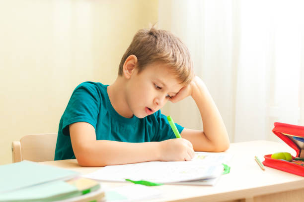 istock 7 yeas old boy sitting at desk and doing homework 1292298951