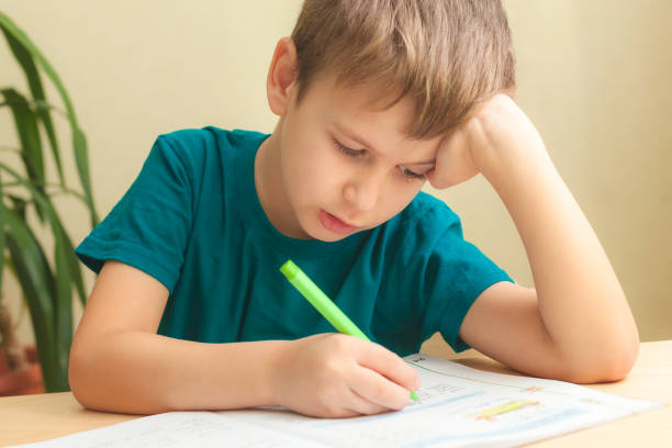 istock 7 yeas old boy sitting at desk and doing homework 1292298974