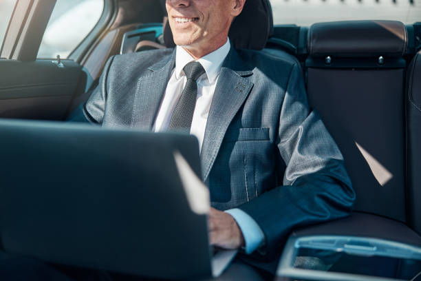 istock Cheerful elegant man with laptop in car 1292299901