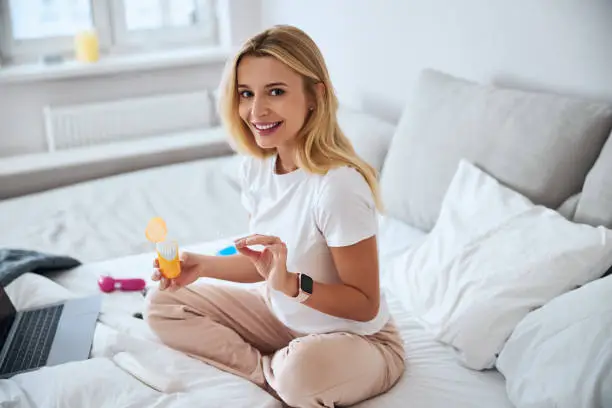 Photo of Happy young lady spending time went beauty product on bed in home apartments