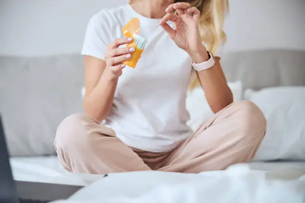 Photo of Blonde female with cosmetics products in arms spending morning time in home