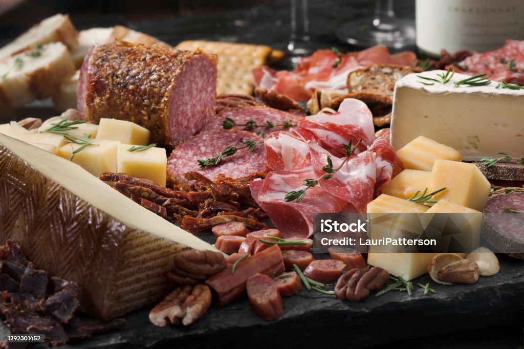 Charcuterie Board Cured Meat and Cheese Platter with Nuts, Crackers, Crusty Bread and White Wine Charcuterie Stock Photo