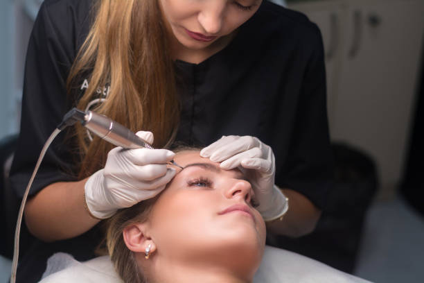 istock Permanent eyebrow makeup. Cosmetologist applying tattooing of eyebrows. 1292303625