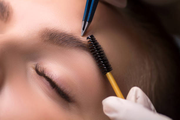 istock Beautician plucking eyebrows. Eyebrow care in a beauty salon. 1292303676