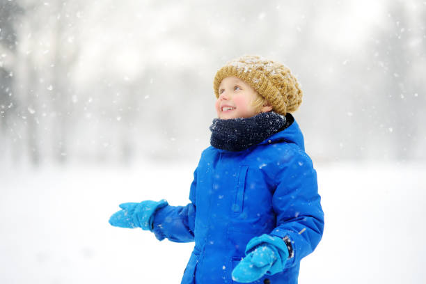 istock Little boy having fun playing with fresh snow during snowfall. Admiring baby catching snowflakes on gloves. Active outdoors leisure for child on snowy winter day. 1292307391