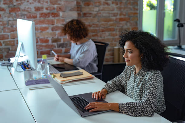 istock Two businesswomen working side by side in the office, using technology 1292307447