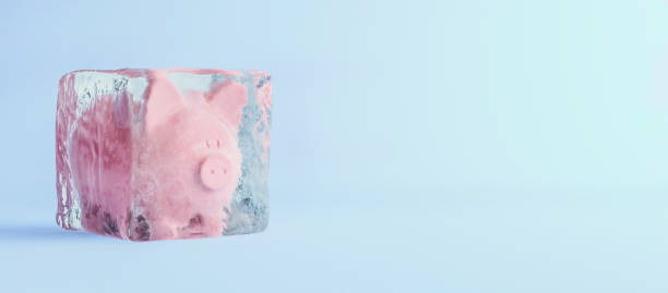 розовая копилка, замороженная в кубике льда, концепция замороженного счета, плоский синий фон, 3d render - frozen currency finance ice стоковые фото и изображения