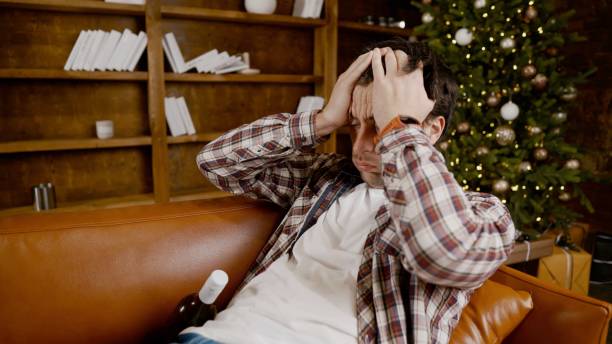 istock Alcohol addiction at young age. Caucasian male cannot stop drinking alcohol, drunken lonely male drinks wine from bottle. Loneliness, depression and alcoholism during Christmas and New Year holidays 1292314532