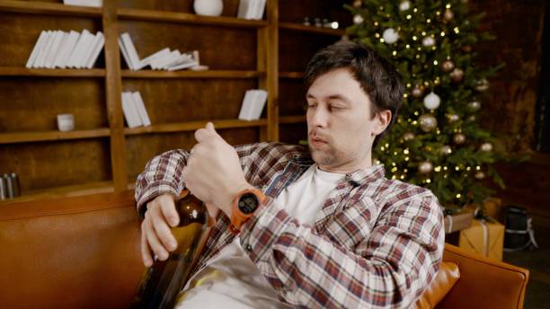 istock Alcohol addiction at young age. Caucasian male cannot stop drinking alcohol, drunken lonely male drinks wine from bottle. Loneliness, depression and alcoholism during Christmas and New Year holidays 1292314542
