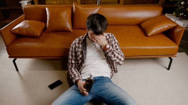 istock Alcohol addiction at young age. Caucasian male cannot stop drinking alcohol, drunken lonely male drinks wine from bottle. Loneliness, depression and alcoholism during Christmas and New Year holidays 1292314588