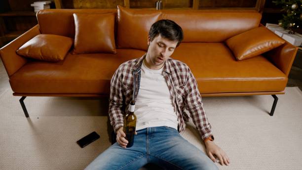 istock Alcohol addiction at young age. Caucasian male cannot stop drinking alcohol, drunken lonely male drinks wine from bottle. Loneliness, depression and alcoholism during Christmas and New Year holidays 1292315104
