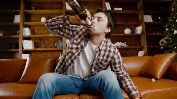 istock Alcohol addiction at young age. Caucasian male cannot stop drinking alcohol, drunken lonely male drinks wine from bottle. Loneliness, depression and alcoholism during Christmas and New Year holidays 1292315148