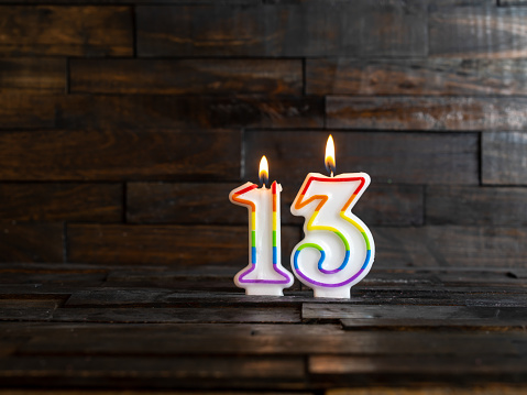 Burning Candles in the form of 13 on a rustic wood background.