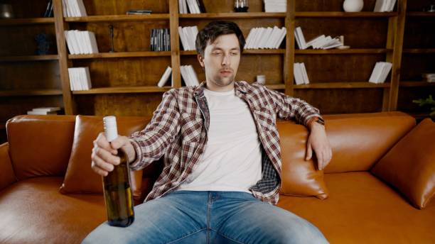 istock Alcohol addiction at young age. Caucasian male cannot stop drinking alcohol, drunken lonely male drinks wine from bottle. Loneliness, depression and alcoholism during Christmas and New Year holidays 1292315169