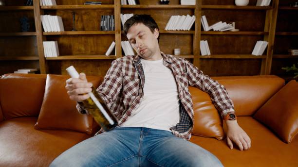 istock Alcohol addiction at young age. Caucasian male cannot stop drinking alcohol, drunken lonely male drinks wine from bottle. Loneliness, depression and alcoholism during Christmas and New Year holidays 1292315249