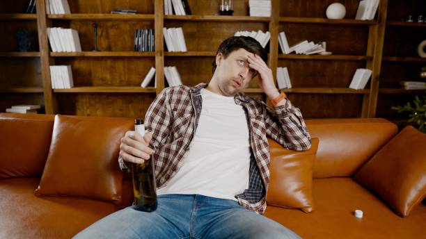 istock Alcohol addiction at young age. Caucasian male cannot stop drinking alcohol, drunken lonely male drinks wine from bottle. Loneliness, depression and alcoholism during Christmas and New Year holidays 1292315279
