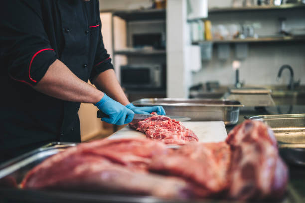 istock Male butcher cut raw meat with sharp knife in restaurants kitchen 1292315346