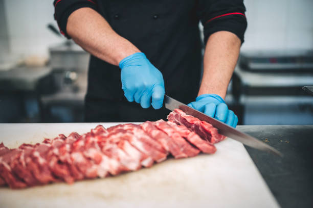istock Male butcher cut raw meat with sharp knife in restaurants kitchen 1292315354