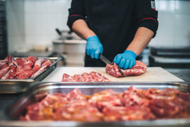 istock Male butcher cut raw meat with sharp knife in restaurants kitchen 1292315365