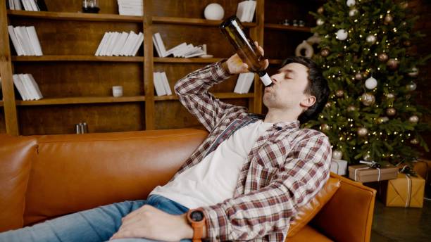 istock Alcohol addiction at young age. Caucasian male cannot stop drinking alcohol, drunken lonely male drinks wine from bottle. Loneliness, depression and alcoholism during Christmas and New Year holidays 1292315374