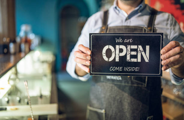 istock Man with apron holding opening sign inside. 1292315376