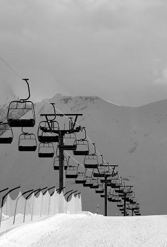 Black and white view on snowy skiing piste and ropeway. Caucasus Mountains. Georgia, region Gudauri in evening.