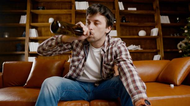 istock Alcohol addiction at young age. Caucasian male cannot stop drinking alcohol, drunken lonely male drinks wine from bottle. Loneliness, depression and alcoholism during Christmas and New Year holidays 1292315549