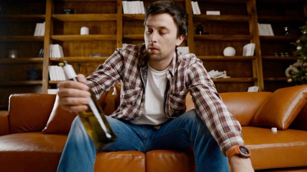 istock Alcohol addiction at young age. Caucasian male cannot stop drinking alcohol, drunken lonely male drinks wine from bottle. Loneliness, depression and alcoholism during Christmas and New Year holidays 1292315682
