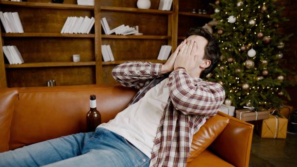 istock Alcohol addiction at young age. Caucasian male cannot stop drinking alcohol, drunken lonely male drinks wine from bottle. Loneliness, depression and alcoholism during Christmas and New Year holidays 1292315737